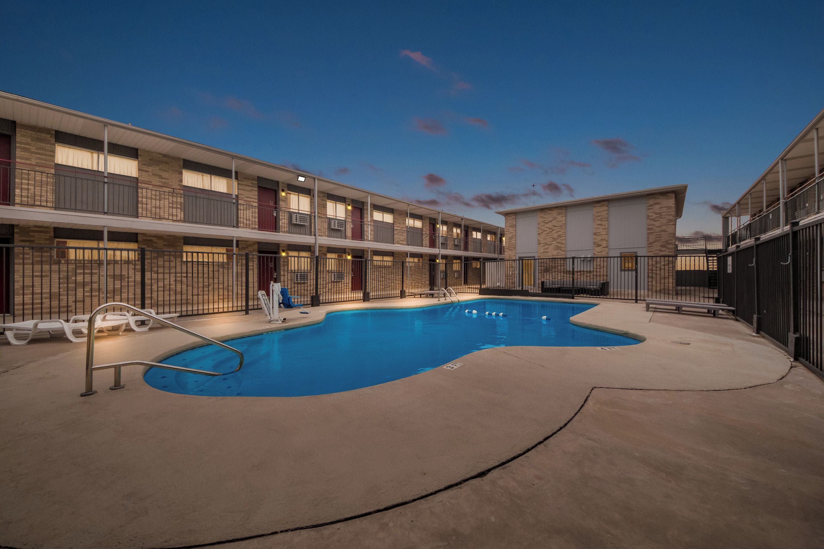 A hotel with a swimming pool, outdoor seating, and a multi-story building with balconies.