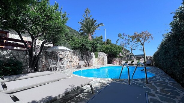 Zona de piscina con sillas de descanso y un muro de piedra.