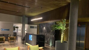 A lobby with a reception desk, a large flat-screen TV, and seating areas with green cushions. - Exclusive apartment in Residencial Vía Montejo (merida)