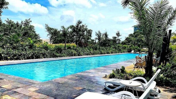A swimming pool with lounge chairs and palm trees in the background. - Exclusive apartment in Residencial Vía Montejo (merida)