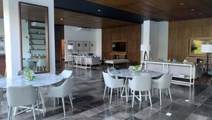 A modern hotel lobby with a dining area, seating, and a television. - Exclusive apartment in Residencial Vía Montejo (merida)