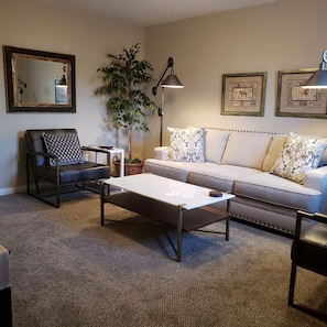 Un salon comprenant un canapé, un fauteuil, une table basse et un lampadaire.