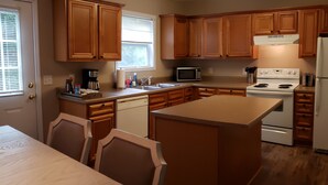 A compact kitchen with wooden cabinets, a microwave, a stove, and a refrigerator.