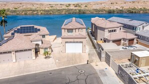 Un quartier résidentiel où les maisons sont dotées de panneaux solaires, d’un garage et offrent une vue sur une rivière.