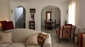 Una sala de estar con sofá, sillones, una mesa de comedor y una escalera.