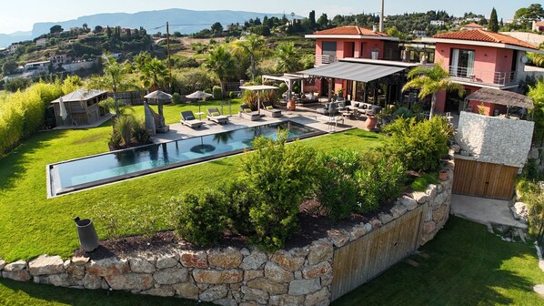 A modern villa with a swimming pool, outdoor seating, and a stone retaining wall. - Villa With Heated Pool Sea View (Nice)