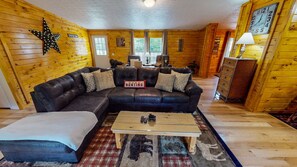 Ein gemütliches Blockhäuschen-Interieur mit einer Eckcouch, einem Couchtisch und einer Stern-Dekoration an der Wand.
