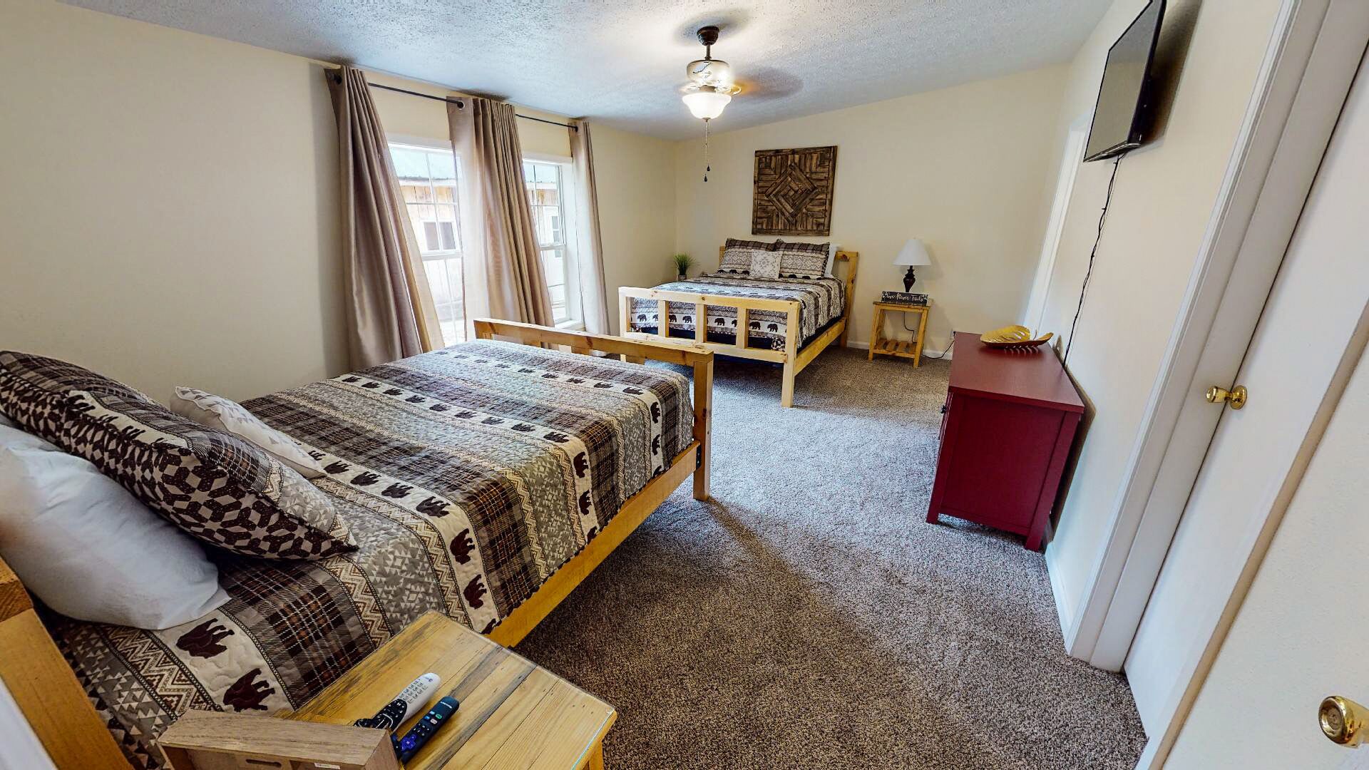 A bedroom with a bed, a desk, a chair, a small table, a lamp, and a wardrobe.