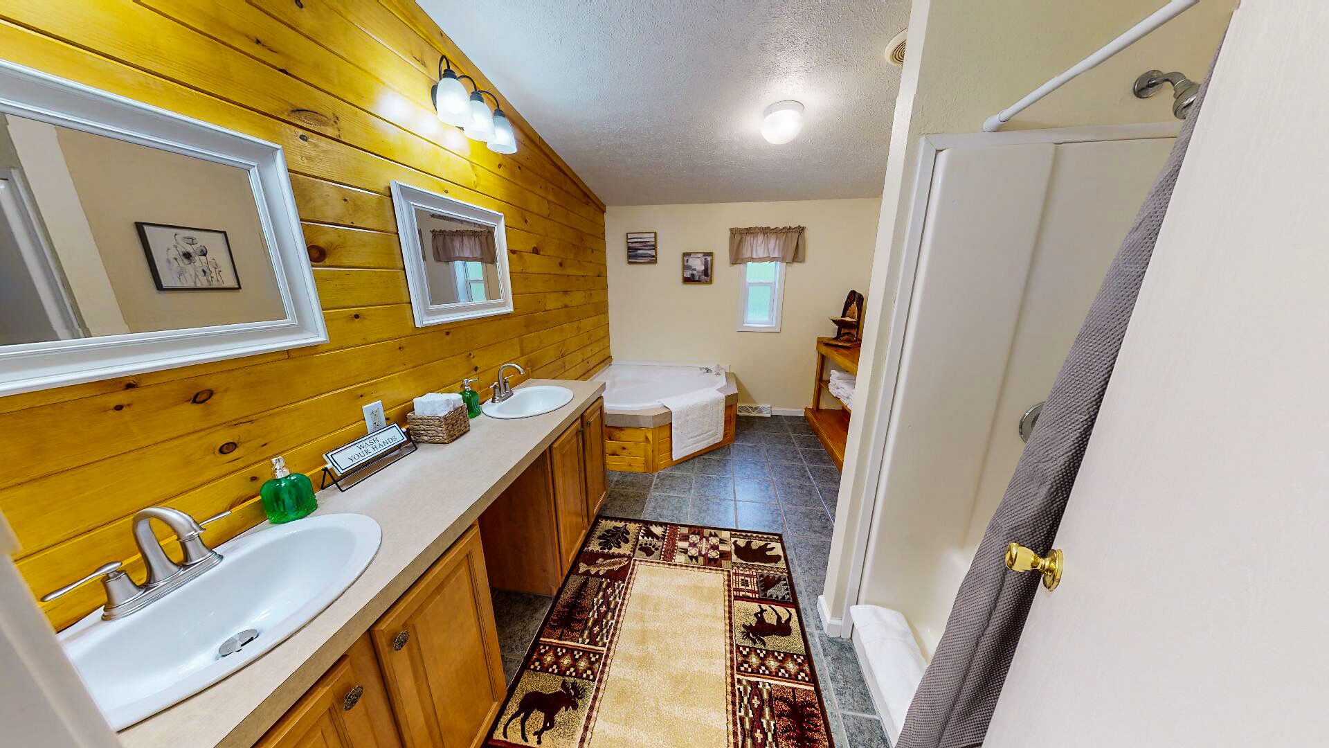 Une salle de bain avec des lambris en bois, deux lavabos, une baignoire et une douche.