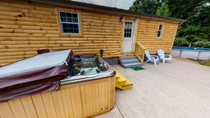 Uma cabana de madeira com banheira de hidromassagem, área de estar externa e uma piscina pequena.
