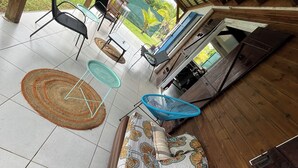 A covered outdoor seating area with a sofa, chairs, and a table. - Creole-style house with a pool and access to the river (Lamentin)