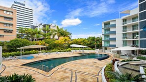 Um hotel moderno com piscina, espreguiçadeiras e um jardim paisagístico.