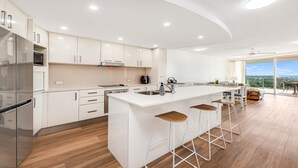 Cozinha moderna com ilha central, banquetas e vista para o exterior.