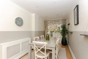 A dining area with a table, chairs, a clock, and a potted plant.