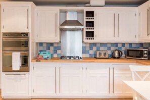Enjoy cooking in this well-equipped kitchen with a stainless steel range hood, oven, toaster, and microwave.