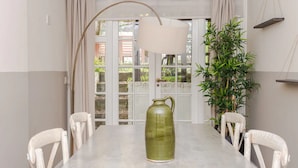 A dining area with a table, chairs, a hanging lamp, a potted plant, and a window with curtains. - Beautiful 5 Bedroom Home With Garden in South Kensington (London)
