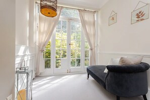 Relax in this serene space with a sofa, artworks, and a table near a large window.
