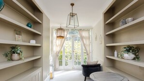 A room with a central seating area, a window with curtains, and shelves with decorative items. - Beautiful 5 Bedroom Home With Garden in South Kensington (London)