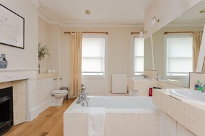 A modern bathroom with a bathtub, toilet, sink, and a large mirror.