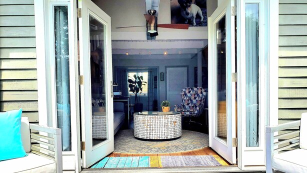 Un interior modern amb una entrada de porta de vidre, una taula rodona amb disseny i un sofà amb coixí blau.