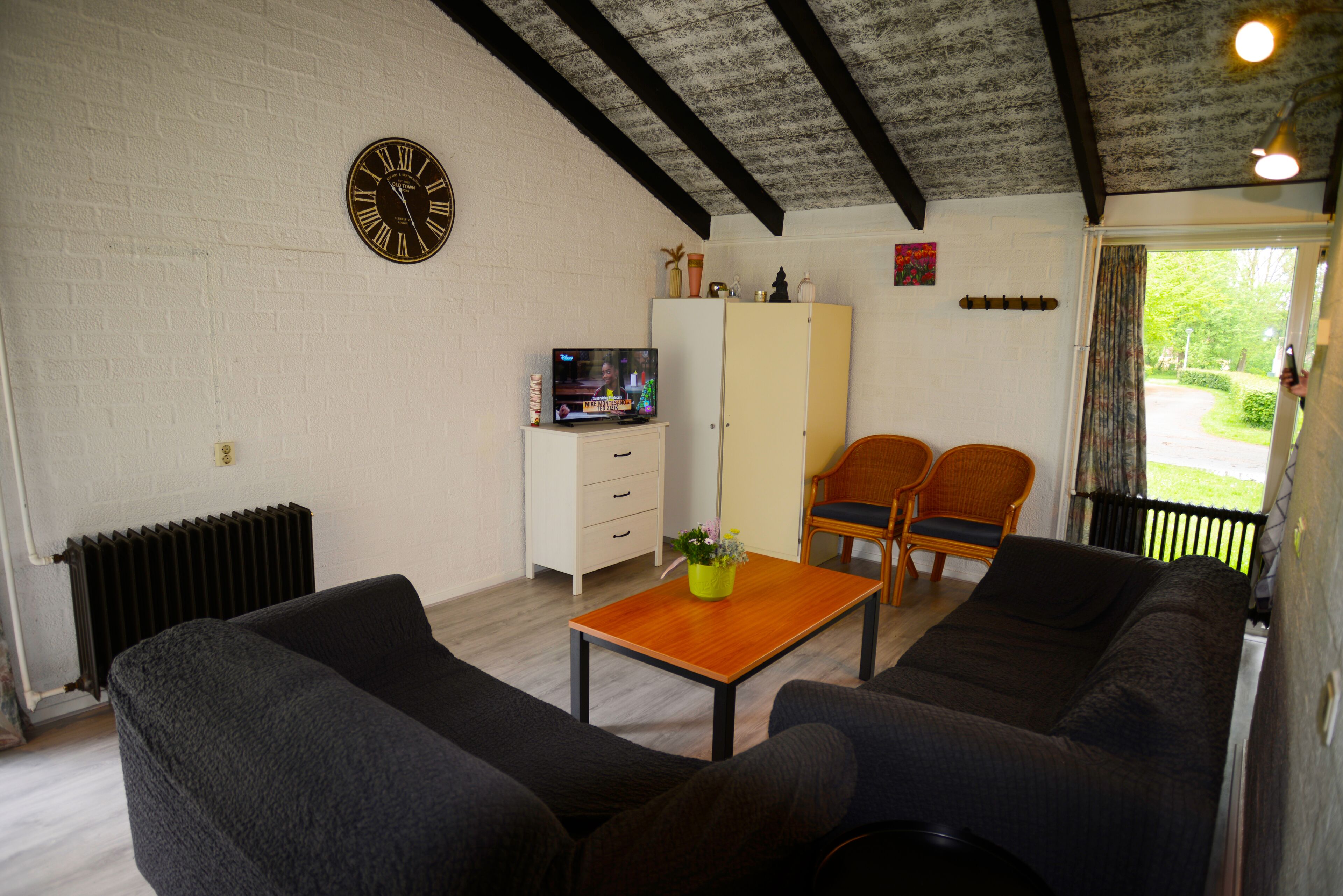 Una sala de estar con sofá, televisión, mueble y ventana con cortinas.
