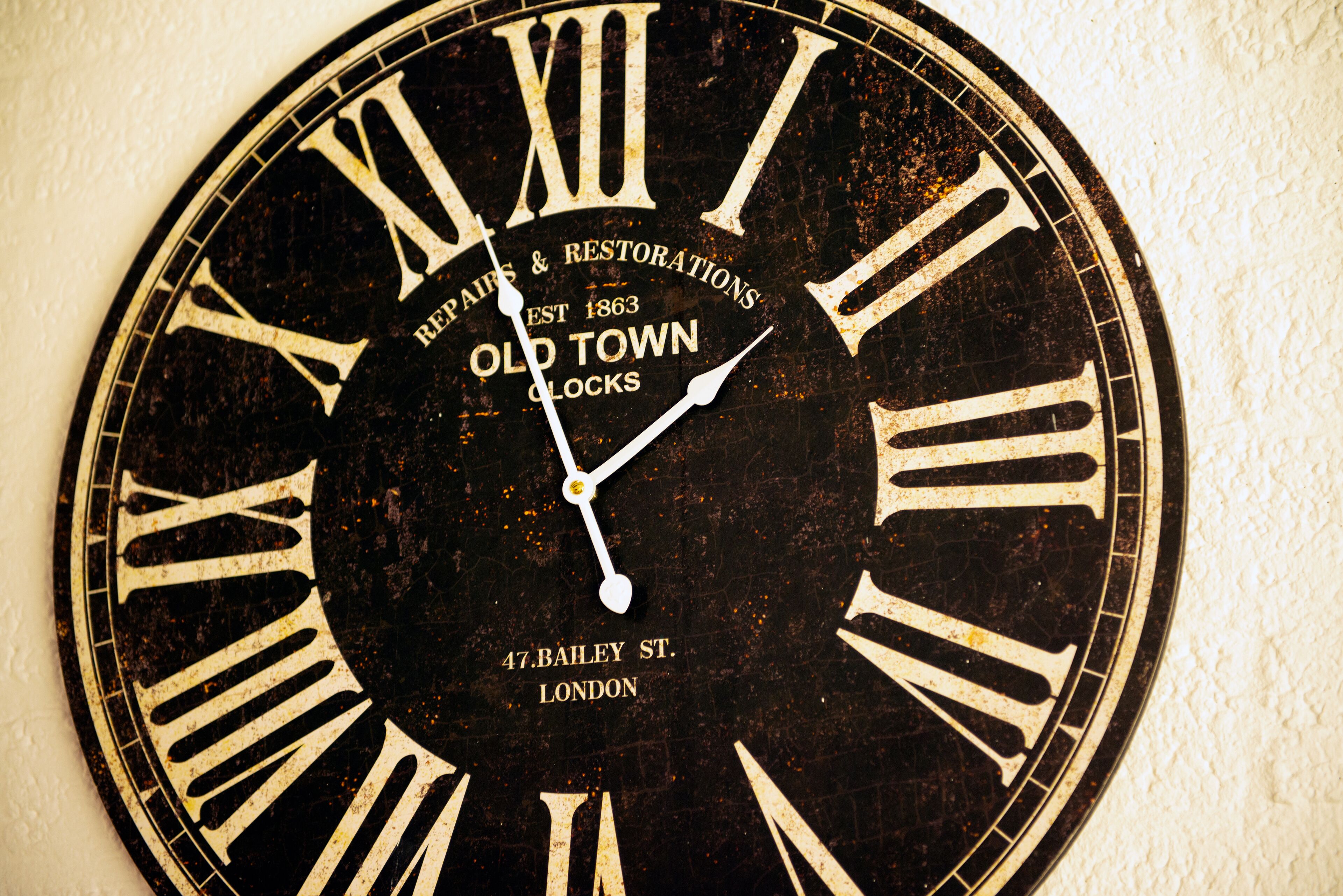A wall-mounted clock with Roman numerals and text indicating it is from Old Town Clocks, established in 1863, located at 47 Bailey St., London.