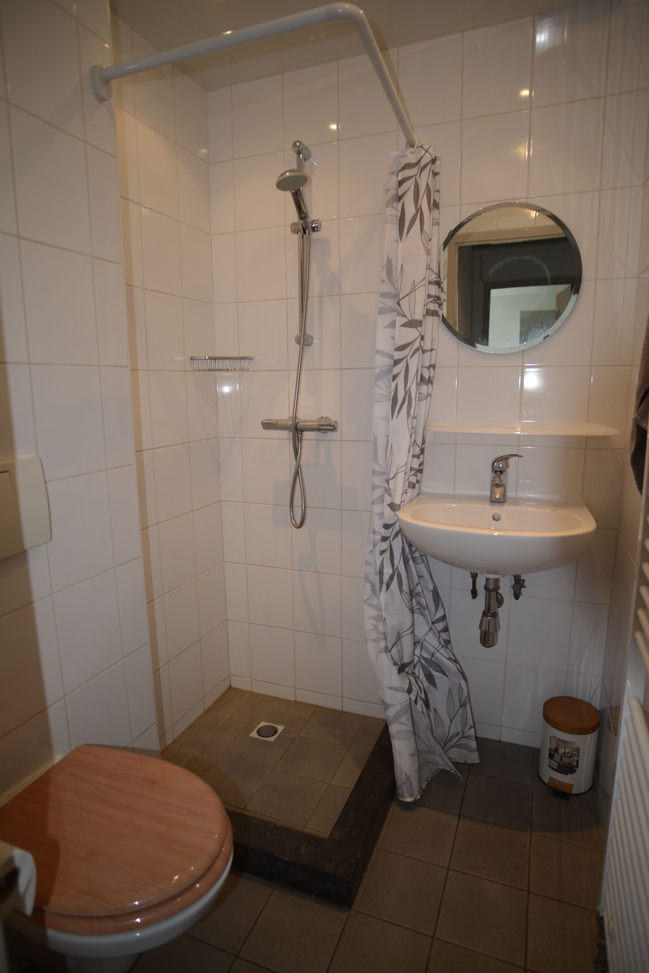 Un baño con ducha, inodoro, lavamanos y espejo.