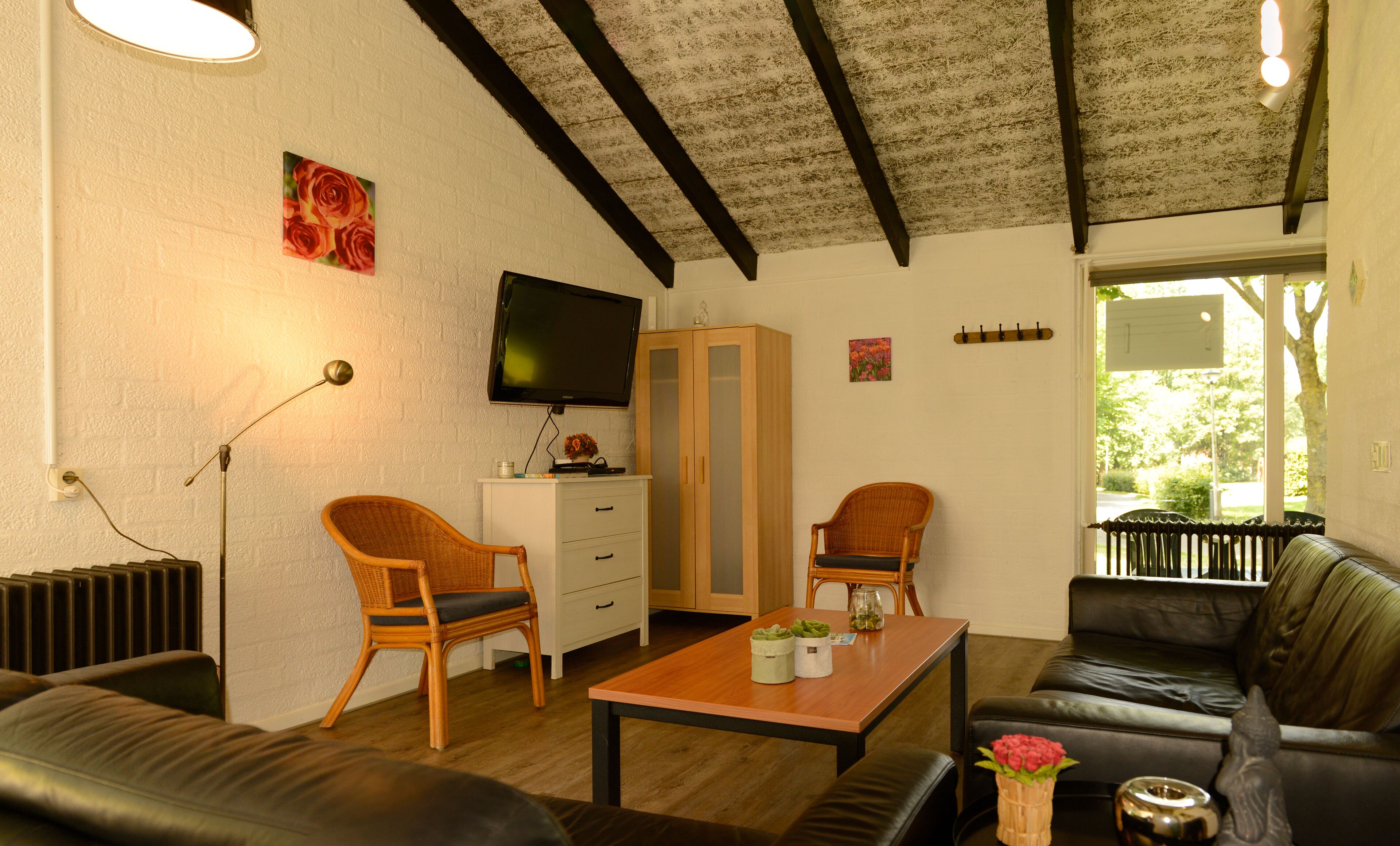A furnished living room with a sofa, chairs, a table, a TV, and a view of the outdoors.
