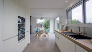 A modern kitchen with a dining area, large windows, and a view of the outdoors. - Tal Er Forn - PLOUHARNEL (PLOUHARNEL)