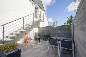 A modern outdoor patio with a staircase, outdoor seating, and a colorful easel. - L'Agapanthe - BELZ - Vacation Home (BELZ)