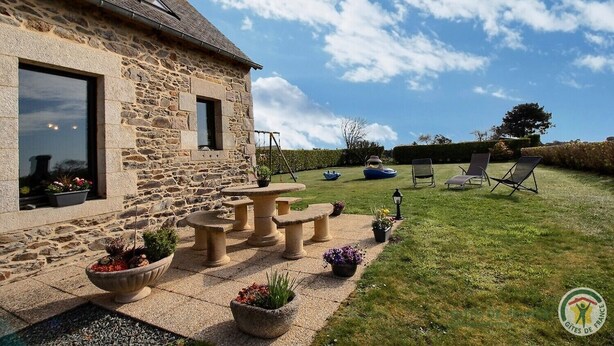 A stone house with a patio featuring outdoor seating and potted plants. - Amzerzo - PLOUBAZLANEC (PLOUBAZLANEC)