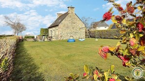 A stone house with a grassy yard, a swing set, and a hedge. - Amzerzo - PLOUBAZLANEC (PLOUBAZLANEC)