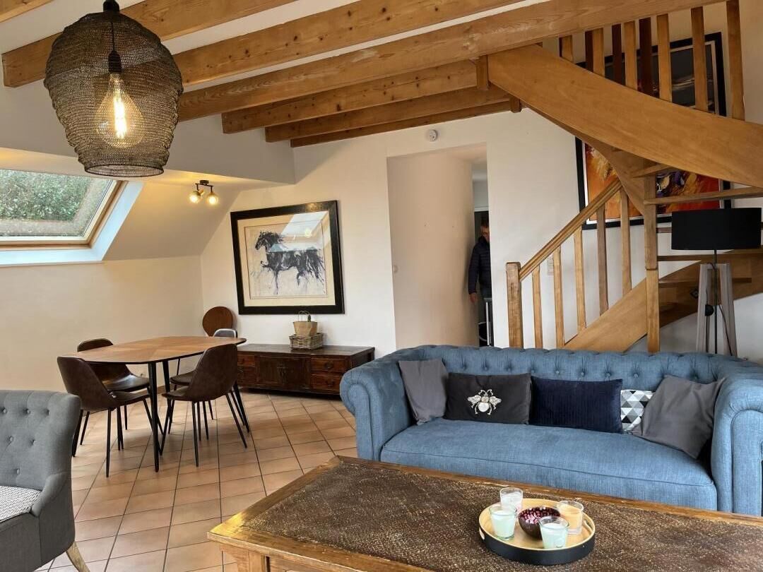 A cozy living room with a blue sofa, a wooden coffee table, and a dining area with a table and chairs.