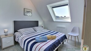 Ein Schlafzimmer mit einem Bett, einem Nachttisch, einem Stuhl, einem Fenster und einer Heizung.