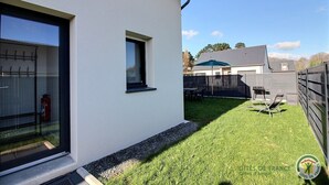 Ein modernes Gebäude mit weißer Fassade, einem kleinen Fenster und einem sichtbaren Feuerlöscher.