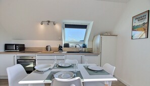 A modern kitchen with a window, a dining table set for four, and a microwave on the counter.