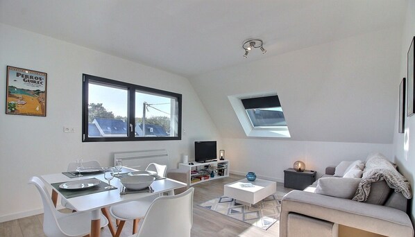 A modern apartment with a dining area, a living room, and a large window with a view.