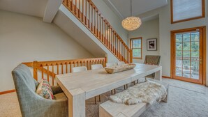 Un comedor con una escalera de madera, una mesa grande y vistas al exterior.