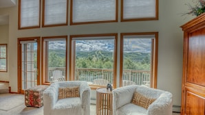 Una habitación acogedora con dos sillones blancos, una mesita de madera y vistas a una terraza con un paisaje pintoresco.