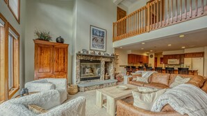 Un salón espacioso con chimenea, muebles de madera y un alto techo con balcón.