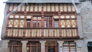 Ein traditionelles Fachwerkhäuschen mit Steinverkleidung, großen Fenstern und einer Holztür.