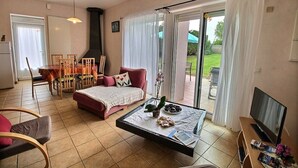 Een woonkamer met een bank, salontafel, televisie en een eethoek met stoelen en een tafel.