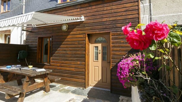 A wooden house with a door, windows, and a small porch area. - Kerborn - PLOUGUIEL - Gîte (PLOUGUIEL)