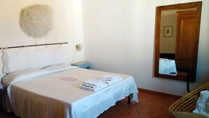 A bedroom with a bed, a bedside table, a chair, a mirror, and a wall-mounted decorative item. - COSY 1/2 mile to sea (Livorno)