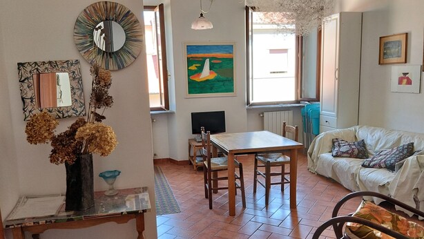 A cozy living room with a dining area, a bookshelf, and a large window providing natural light. - COSY 1/2 mile to sea (Livorno)