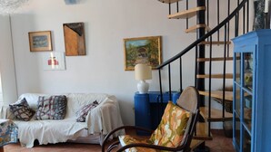 A living room with a sofa, a rocking chair, a blue cabinet, and a staircase. - COSY 1/2 mile to sea (Livorno)