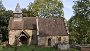 Une petite église historique, dotée d’un clocher en flèche, d’une porte en bois et d’une façade en briques.