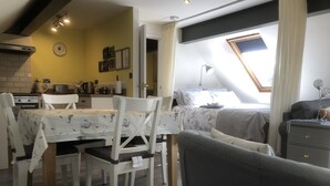 Une pièce confortable comprenant un coin repas, un lit et une petite kitchenette.