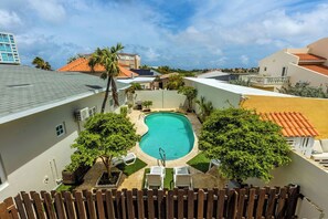 Une piscine entourée de verdure et de bâtiments.