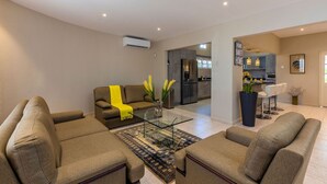 A modern living room with a glass coffee table, two sofas, and a kitchen in the background. - Sleeps 16 @ Palm Beach - 6BR Villa w/ Private Pool (Palm Beach)